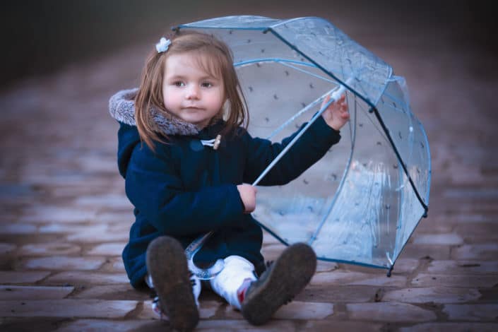 Séance photo en extérieur près de Lille fille avec parapluie sur chemin pavé