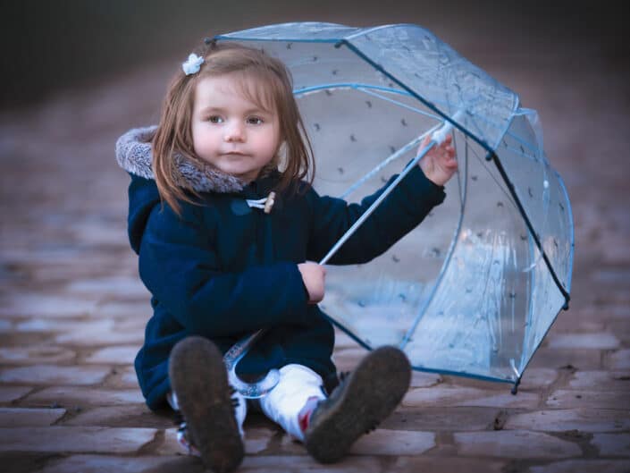 Séance photo en extérieur près de Lille fille avec parapluie sur chemin pavé